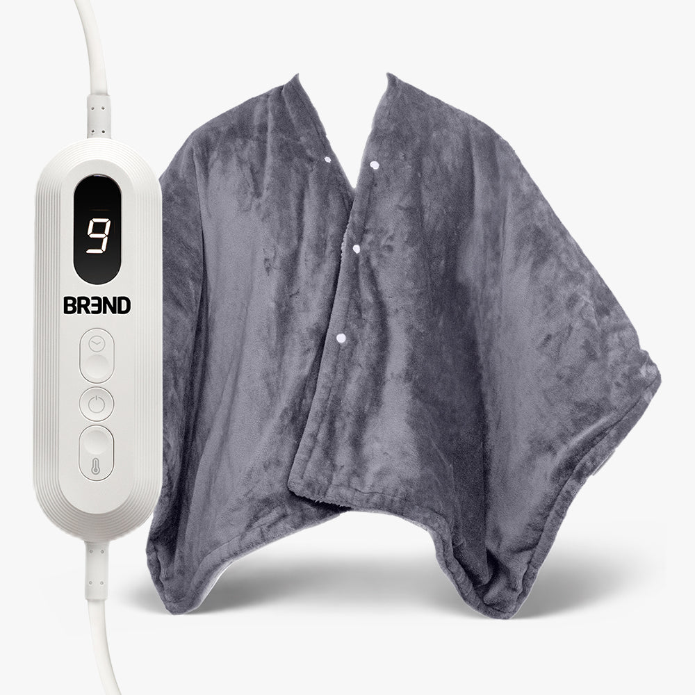 Poncho chauffant électrique gris à boutons-pression, à côté de la télécommande à écran