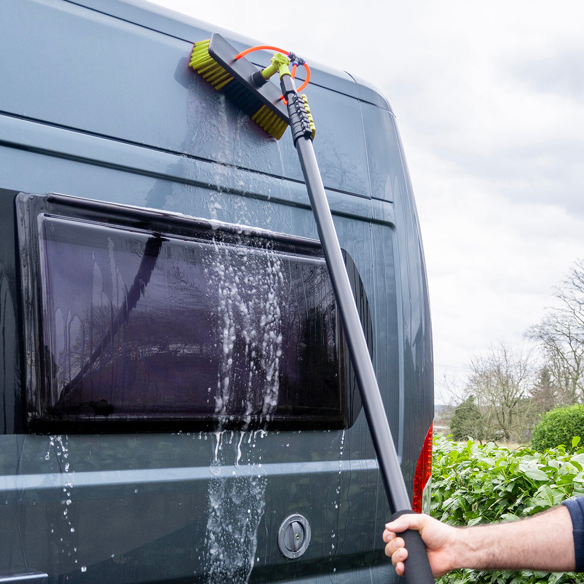 Un camping-car est lavé avec la brosse de lavage traversée par l'eau