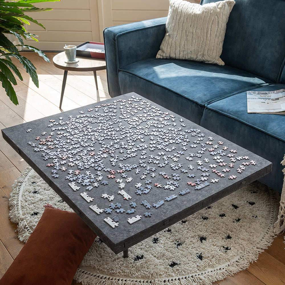 Vilten puzzelplaat met puzzelstukjes op een salontafel, de lades gesloten