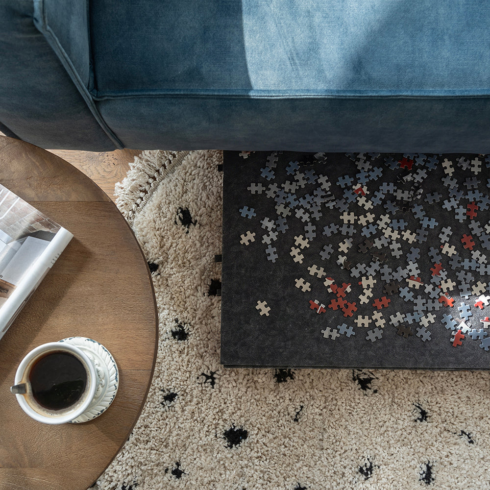 Vilten puzzelplaat met puzzelstukjes deels onder de bank geschoven