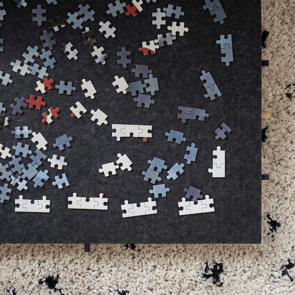 Bovenaanzicht van puzzelstukjes op het antraciet vilt van de puzzelplaat