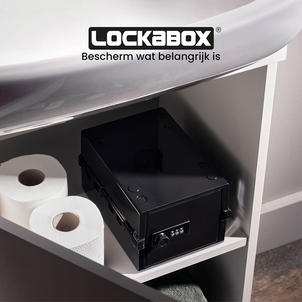 Lockabox Mini noire sur une étagère du meuble de salle de bain, à côté de rouleaux de papier toilette