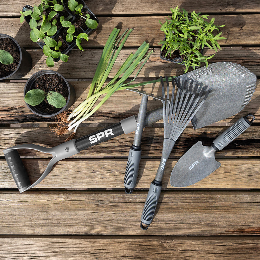 Tuingereedschapset op een houten tafel naast plantjes en lente-uitjes