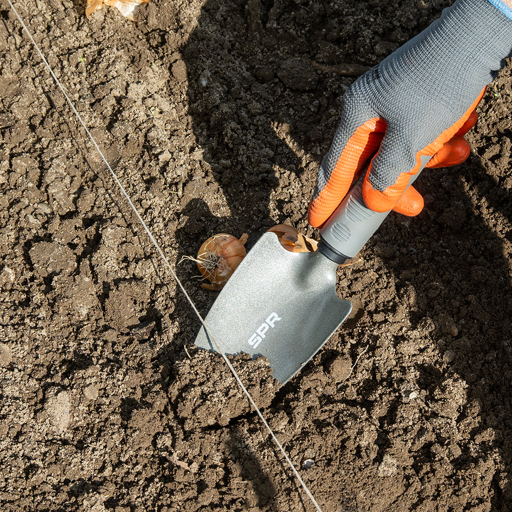Hand graaft met de brede schep een plantgat voor bloembollen